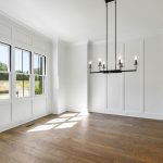 Services A spacious, light-filled room featuring white walls, wooden floors, and a modern chandelier.