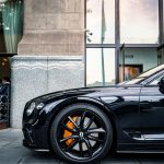 Services Elegant black Bentley parked in front of a modern building showcasing luxury.